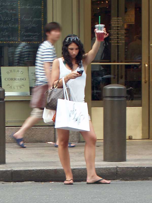 Cena comum: mulher usando celular e esperando um táxi